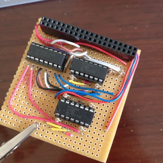 Hand-built stripboard circuit carrying an MCP3008 converter, two MCP6004 amplifier chips, coloured wiring, and a Raspberry Pi header.